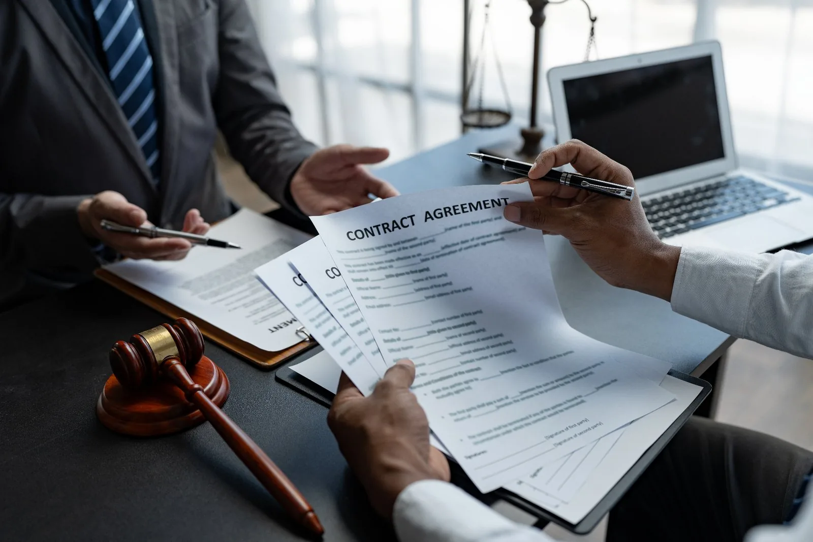 Lawyers reviewing contract agreement with legal documents and scales of justice