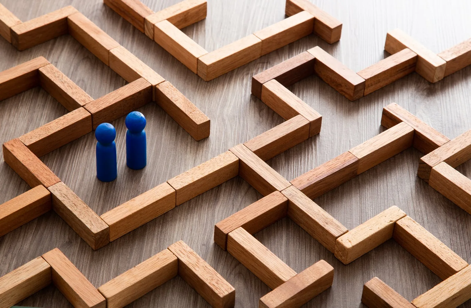 Wooden maze with blue figures representing client journeys and success paths